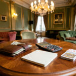 Budget poker casino Paris : préparer sa première session live sans déraper Portefeuille, enveloppe de budget, calculatrice, carnet vierge et cartes à jouer disposés sur une table en bois dans une ambiance élégante parisienne.