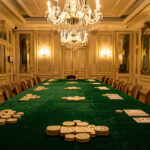 Tournoi de poker à Paris ce week-end : s’inscrire et arriver prêt Salon parisien élégant aux tables recouvertes de velours vert, éclairé par des lustres dorés et préparé pour un événement de stratégie.